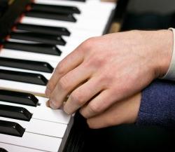 Image of an adult guiding a child's hand on the piano.