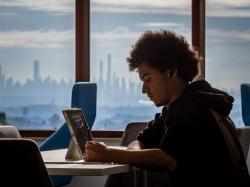 Montclair student studying on laptop with NYC skyline in background